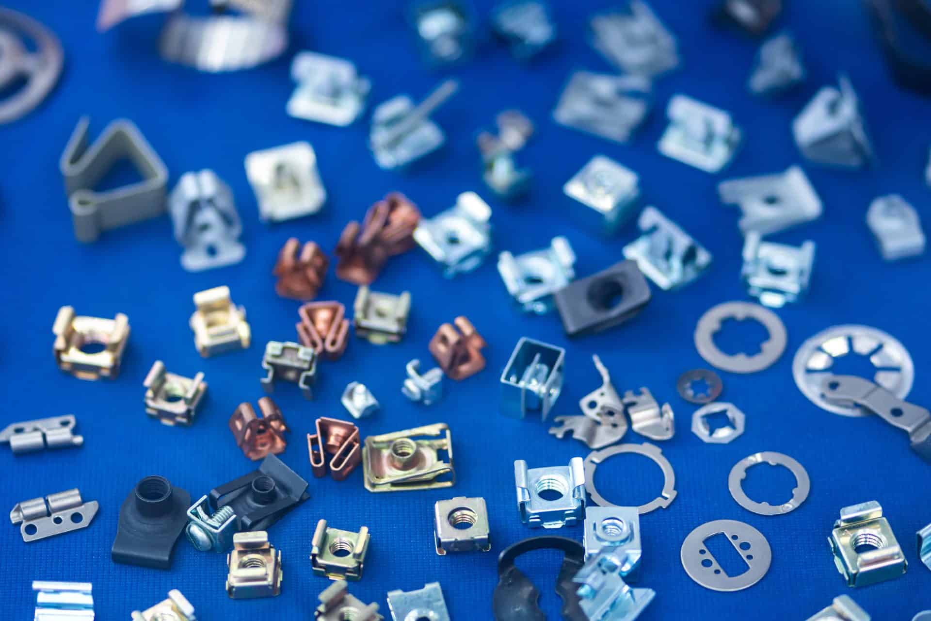 Assorted small metal and plastic mechanical parts are scattered on a blue surface.